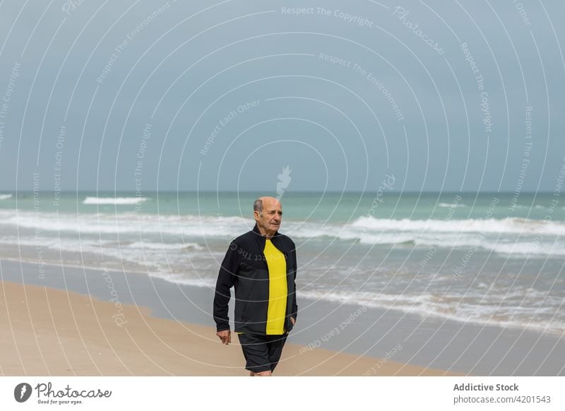 Älterer männlicher Sportler beim Spaziergang am Meer Strand MEER Training winken Fitness Sommer Vitalität Athlet Jogger älter gealtert Senior Wasser Ufer Küste