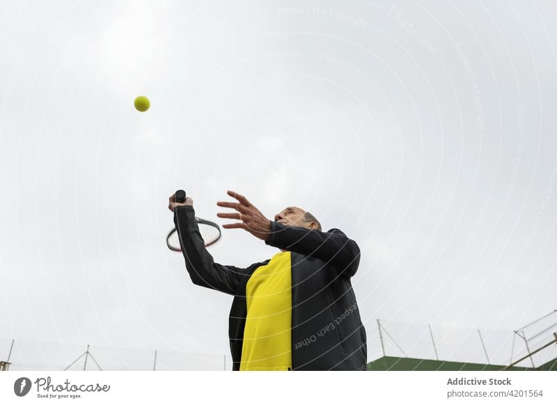 Älterer Mann spielt Tennis auf grünem Platz Sportler spielen Streichholz Training aufschlagen Ball Remmidemmi üben Athlet älter Senior gealtert schießen