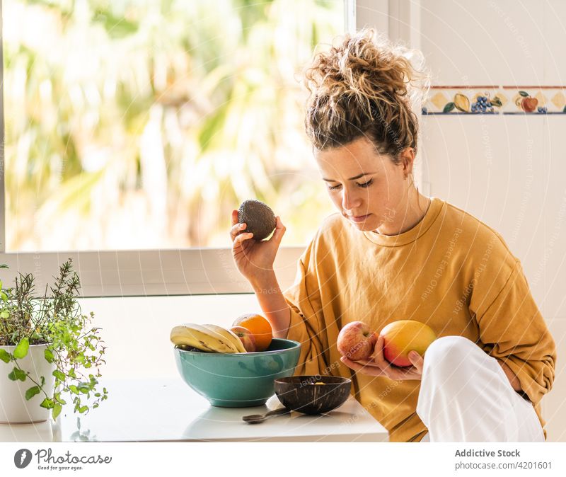 Nachdenkliche Frau wählt Früchte zum Frühstück aus besinnlich nachdenklich Lebensmittel Frucht wählen frisch Gesundheit Wellness Windstille vorbereiten Raum