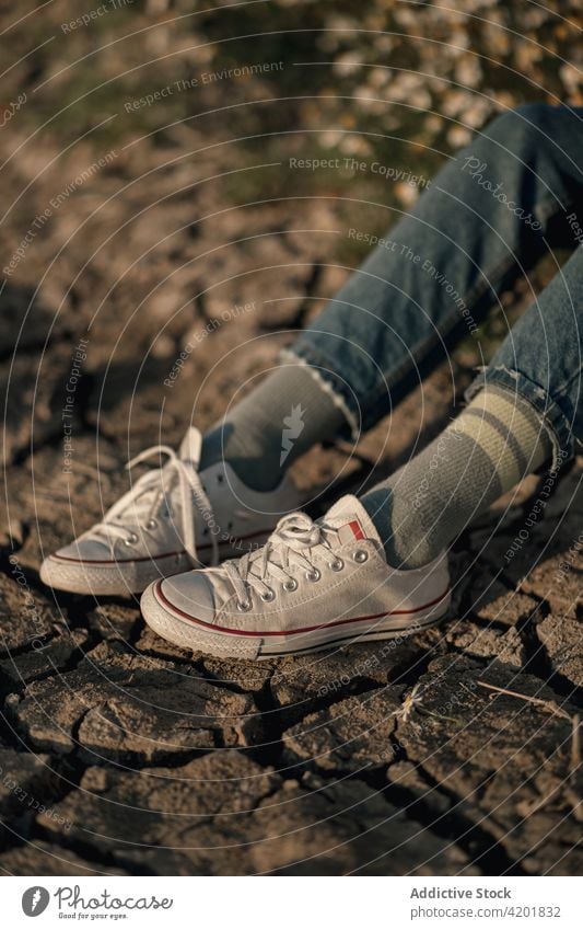 Anonyme Frau im Frühlingsfeld sitzend Feld nachdenken Reisender Natur besinnlich ruhen sich[Akk] entspannen Umwelt Jeanshose allein Landschaft Lifestyle ruhig