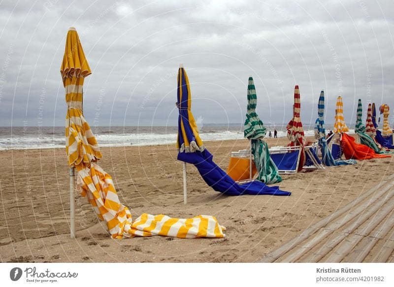 sonnenschirme am strand von trouville gestreift geschlossen sandstrand leer einsam verlassen liegestühle strandpromenade meer küste nebensaison nachsaison