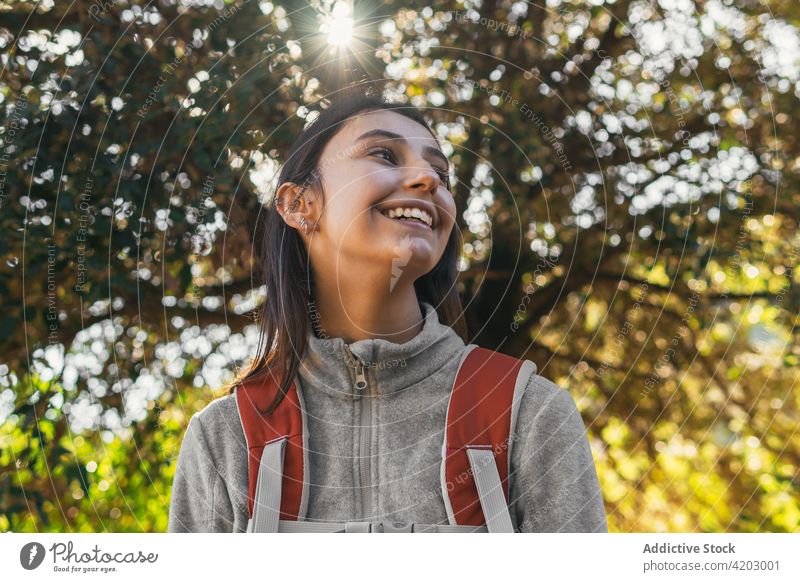 Fröhliche Frau mit Rucksack beim Wandern im Wald Wanderer Glück Sonnenlicht aktiv heiter Natur Lächeln jung Lifestyle Aktivität Erholung Wellness Gesundheit