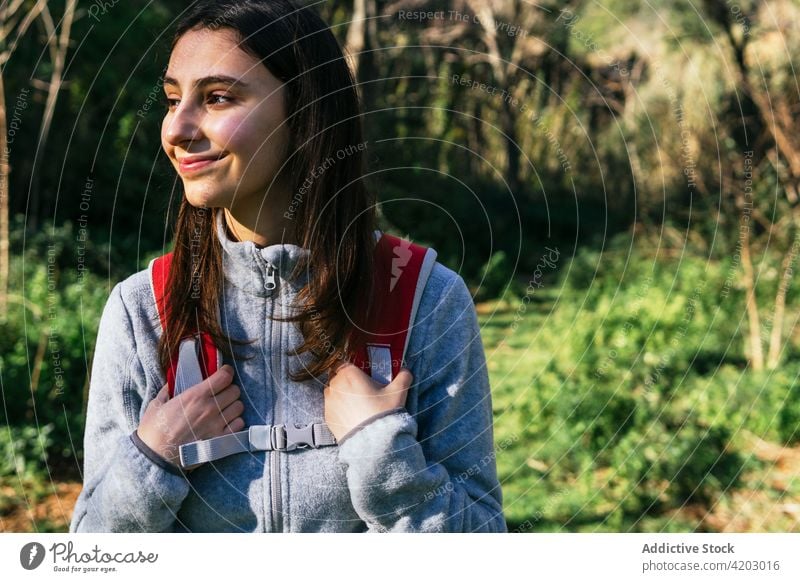 Fröhliche Frau mit Rucksack beim Wandern im Wald Wanderer Glück Sonnenlicht aktiv heiter Natur Lächeln jung Lifestyle Aktivität Erholung Wellness Gesundheit