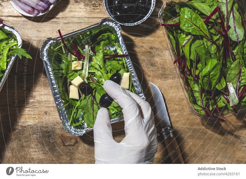 Unbekannte Köchin fügt Oliven zum Gemüsesalat hinzu Küchenchef hinzufügen Bestandteil Salatbeilage Butter oliv Ernährung roh Gesundheit Imbissbude Koch Blatt