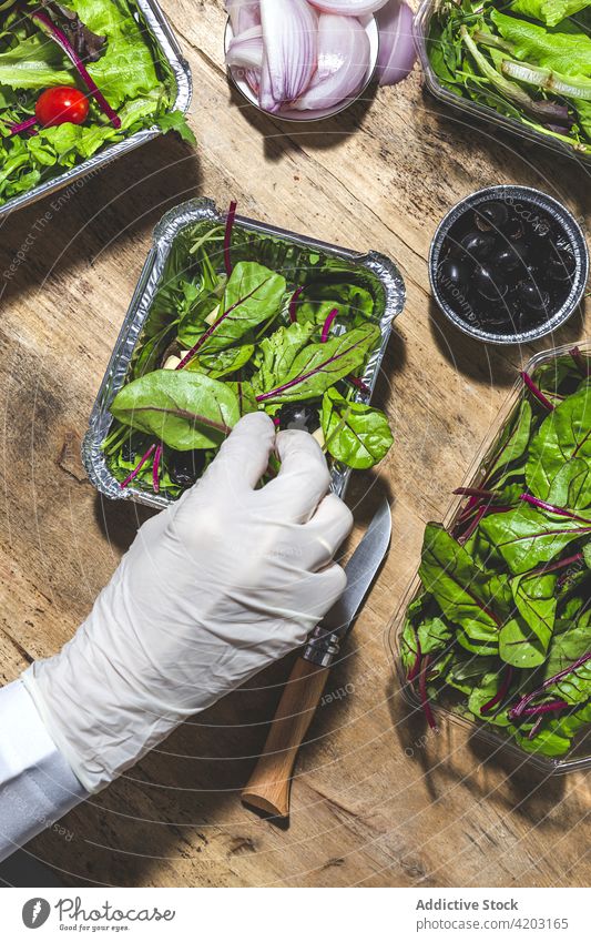 Unbekannte Köchin fügt Oliven zum Gemüsesalat hinzu Küchenchef hinzufügen Bestandteil Salatbeilage Butter oliv Ernährung roh Gesundheit Imbissbude Koch Blatt