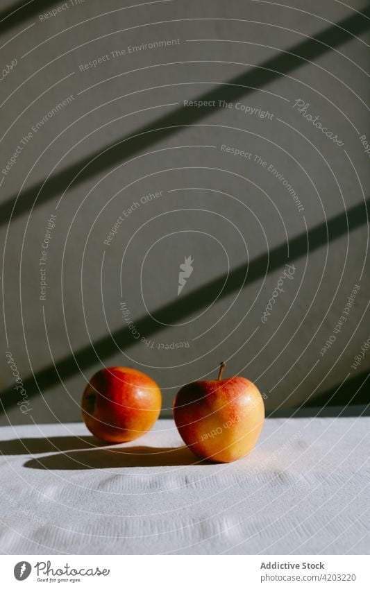 Reife Äpfel auf dem Tisch vor der grauen Wand rot Apfel Frucht frisch reif Lebensmittel ganz Vitamin lecker gesunde Ernährung Tischwäsche geschmackvoll süß