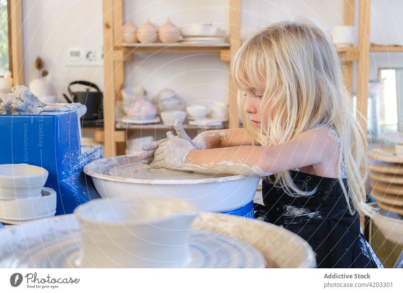 Kleines Kind lernt Töpfern in der Werkstatt Töpferwaren Rad Ton Topf Form Mädchen Frau kreativ Hobby wenig Fähigkeit handgefertigt dreckig Prozess Vase Tisch