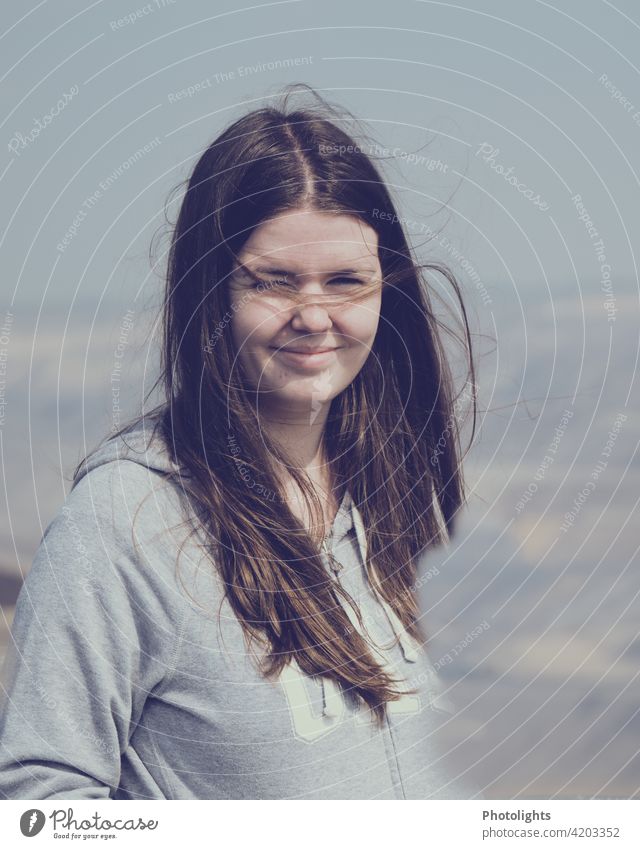 Porträt einer jungen Frau mit langen Haaren und grauem Oberteil braun Sonne sonnig Haare & Frisuren Erwachsene hübsch Mensch Lifestyle Portrait Außenaufnahme