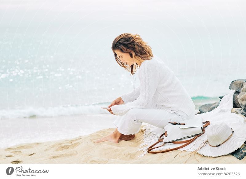 Unbekümmerte Frau benutzt Handy am Meer zuhören Musik Seeküste ruhig Harmonie Gesang Windstille Gelassenheit Strand MEER Küste Ufer Kopfhörer Gerät Apparatur