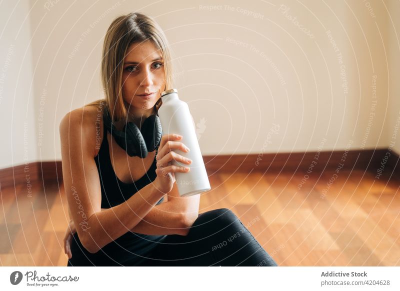 Sportlerin mit Wasserflasche nach dem Training Frau Kopfhörer Flasche Durst Hydrat trinken ruhen Sportkleidung Übung Athlet Raum Fitness Headset Drahtlos Dame