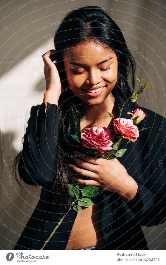 Attraktive hispanische Frau mit Blick auf rosa Rosen Bouquet gegen Sonnenschein Robe Blumenstrauß Schatten Sonnenlicht feminin sanft Angebot Roséwein sinnlich