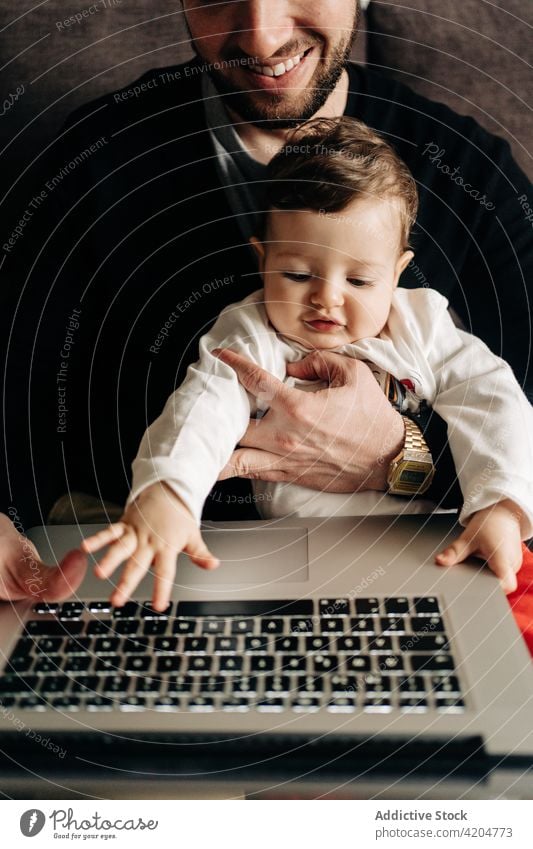 Junger Vater mit kleinem Sohn schaut Video auf Netbook Mann Kind zuschauen Karikatur Laptop Zusammensein Liebe Sofa Partnerschaft heimwärts online Bonden jung