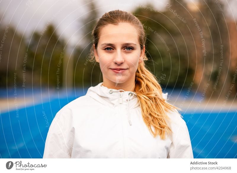 Fröhliche Sportlerin lächelt und schaut in die Kamera Athlet Lächeln Inhalt sonnig Stadion Sportbekleidung professionell Training passen Frau Gesundheit Fitness