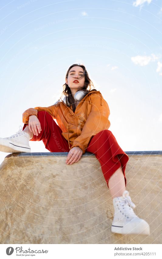 Stylischer Teenager unter blauem, bewölktem Himmel in der Stadt Mode Stil selbstbewusst Individualität cool tausendjährig Blauer Himmel wolkig Zaun ruhen