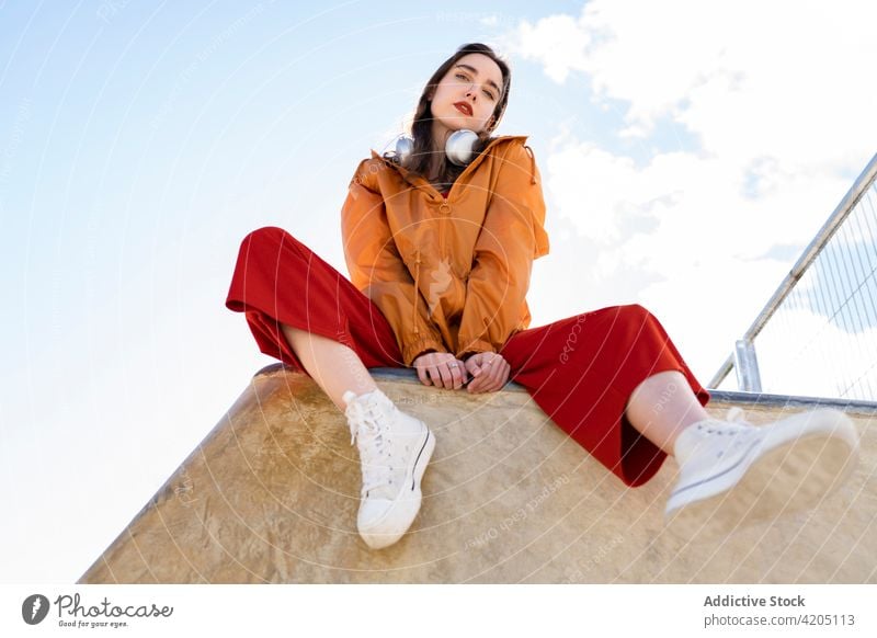 Stylischer Teenager unter blauem, bewölktem Himmel in der Stadt Mode Stil selbstbewusst Individualität cool tausendjährig Blauer Himmel wolkig Zaun ruhen