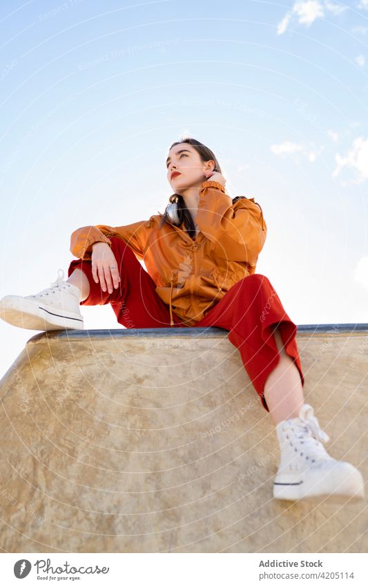 Stylischer Teenager unter blauem, bewölktem Himmel in der Stadt Mode Stil selbstbewusst Individualität cool tausendjährig Blauer Himmel wolkig Zaun ruhen