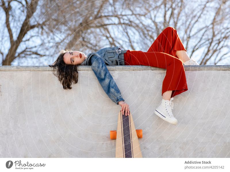 Skateboarder mit Longboard auf der Skateboard-Rampe stehend Frau Skateboarderin ruhen Sport müde erschöpft Himmel Skateplatz urban Sportlerin stylisch wolkig