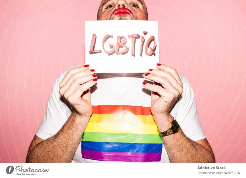 Positive Homosexuell zeigt Papier mit LGBTIQ Aufschrift in rosa Studio Mann Homosexualität schwul Stolz queer lgbt Grimasse Konzept manifestieren Tierhaut