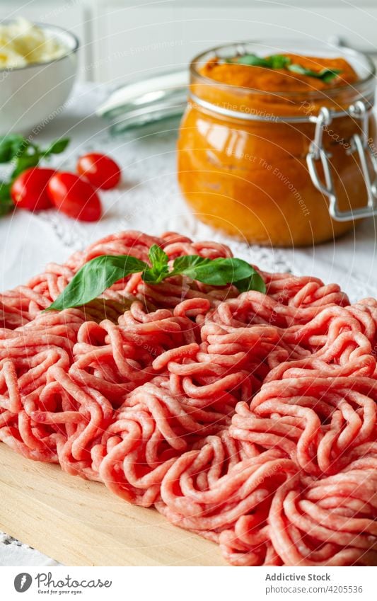 Rohes Hackfleisch und Basilikumblätter auf dem Tisch Fleisch zerkleinern roh frisch Koch kulinarisch Lebensmittel vorbereiten Bestandteil ungekocht