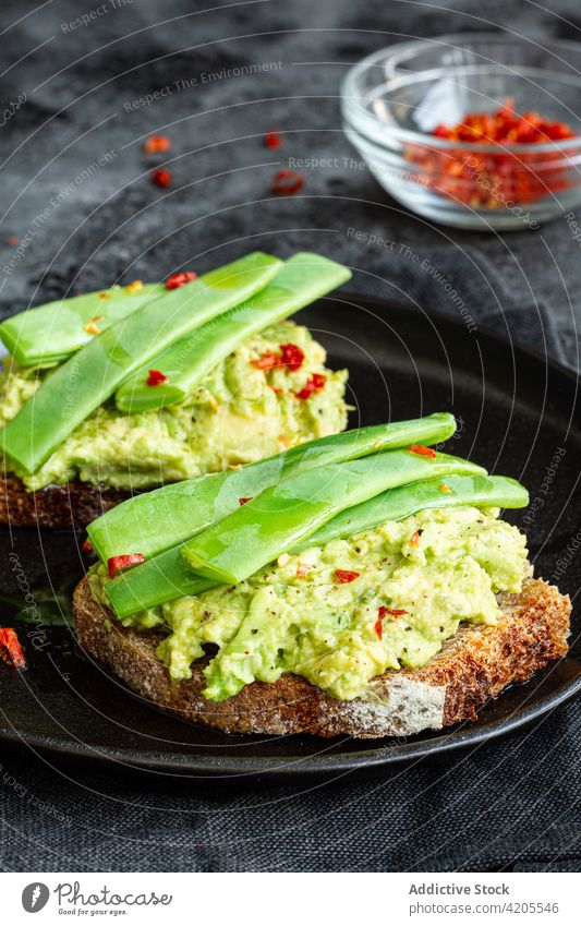 Leckere Toasts mit Guacamole und grünen Erbsenschoten Zuprosten lecker geschmackvoll dienen appetitlich essen Vegetarier Mahlzeit organisch Küche Ernährung