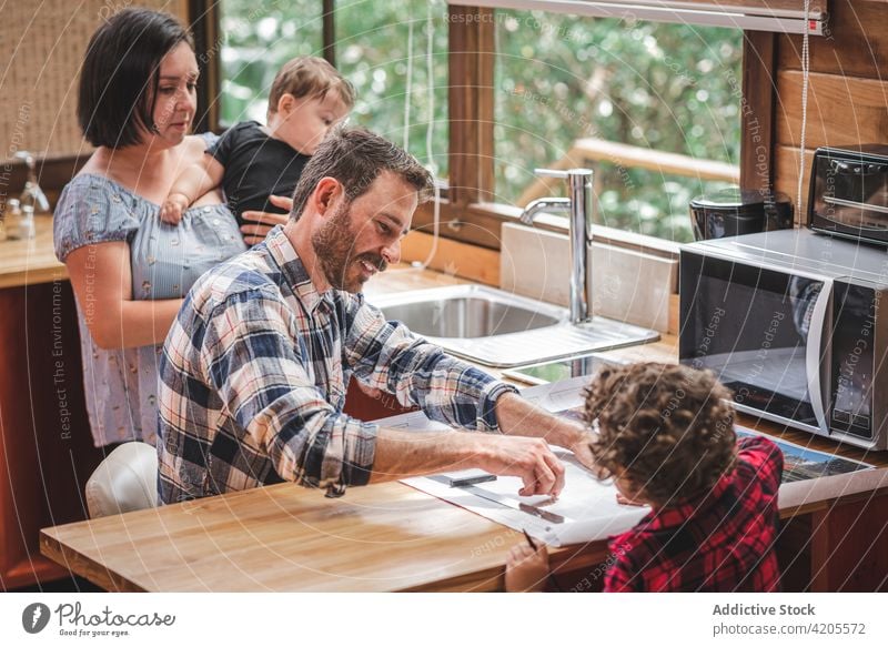 Männlicher Architekt zeichnet Skizze in Küche mit Familie zeichnen Bauplan Zusammensein Tiefgang Design Projekt Haus Gebäude Plan Vater Mutter Kinder