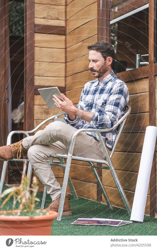 Männlicher Architekt mit Tablet auf der Terrasse eines Hauses Mann Projekt Arbeit Browsen Tablette Bauplan Tiefgang männlich Papier rollen whatman Skizze