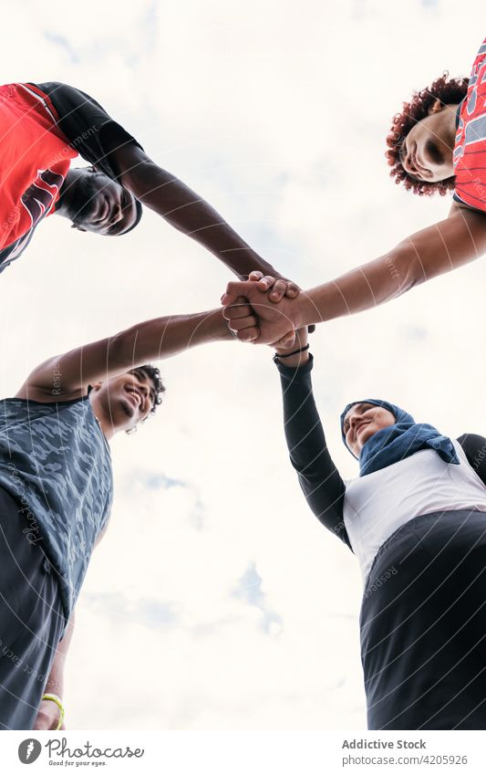 Multiethnisches Streetball-Team stapelt vor dem Spiel die Hände Hände stapeln Basketball Zusammensein Einheit Spieler heiter Sport rassenübergreifend