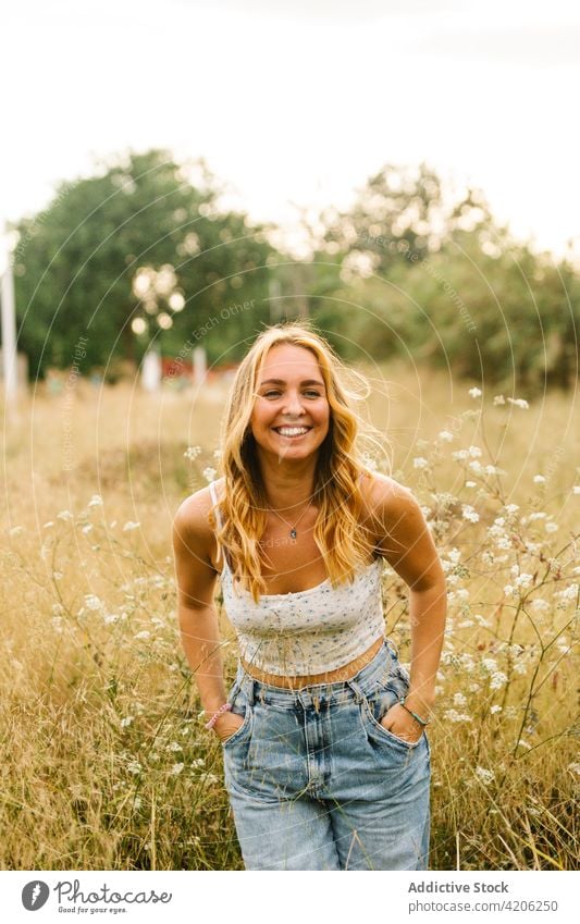 Fröhliche, stilvolle Frau auf einem Feld im Sommer heiter genießen Wiese Freude sorgenfrei Wochenende Sommerzeit Glück positiv Natur Inhalt Lächeln Outfit