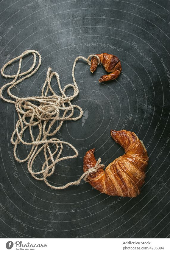 Croissant mit Seil auf schwarzem Hintergrund gebacken Brot Brötchen Lebensmittel frisch Bäckerei Gebäck Frühstück Form Handwerk Küche Ernährung Kruste rustikal