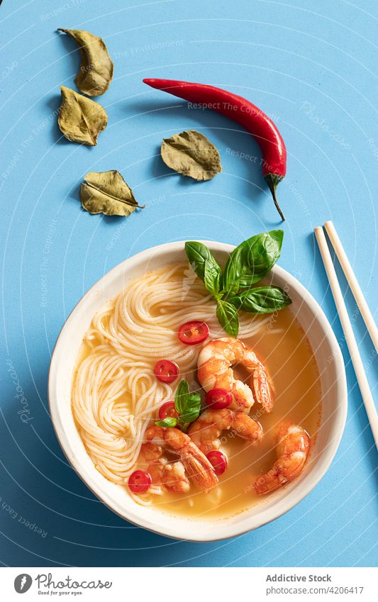 Tom-Yum-Suppe in Schüssel mit Stäbchen auf blauem Hintergrund Thai Blätter Kraut Frische Thai-Food Zitrusfrüchte Nudelschale tom yam kung Asiatische Küche