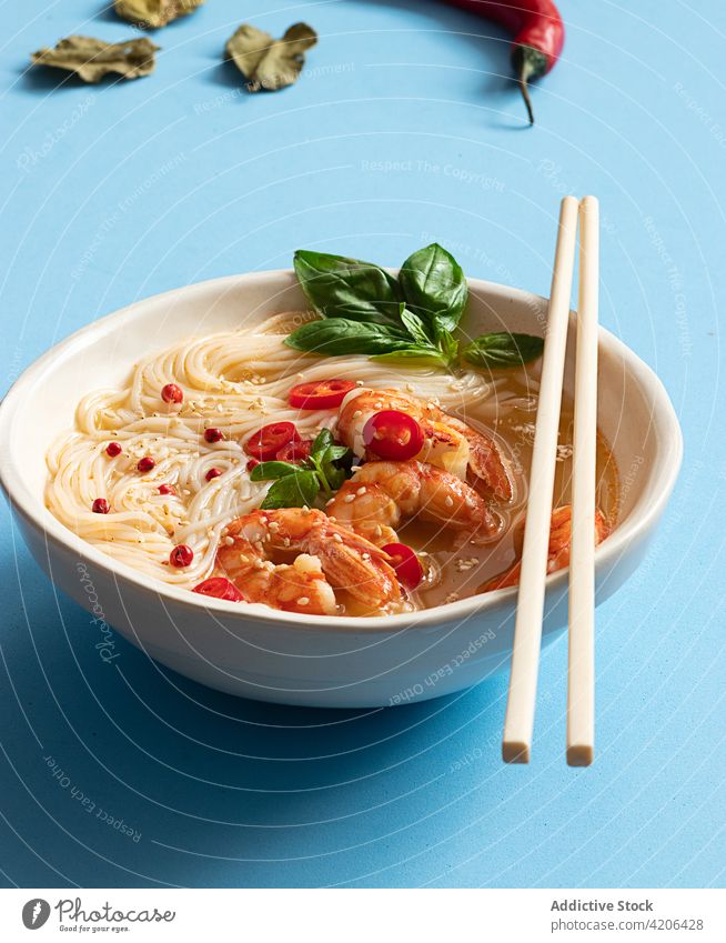 Tom-Yum-Suppe in Schüssel mit Stäbchen auf blauem Hintergrund Thai Blätter Kraut Frische Thai-Food Zitrusfrüchte Nudelschale tom yam kung Asiatische Küche