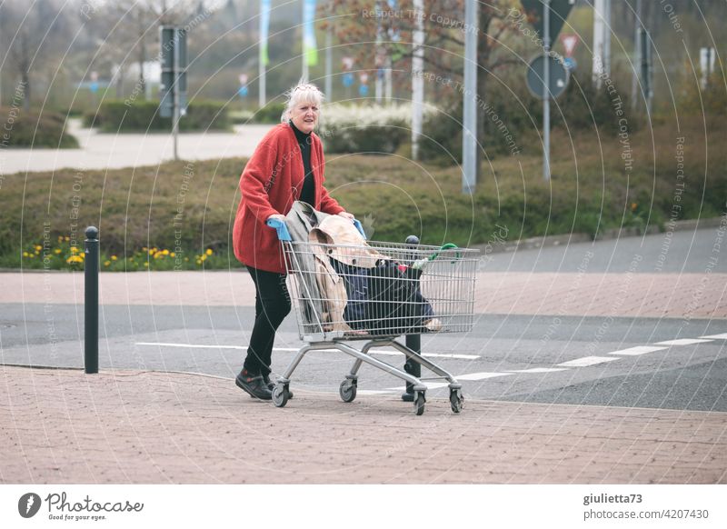 seltsam | Ladendiebin auf der Flucht? Oder was macht die Frau mit dem Einkaufswagen hier? Blick skurril Straße Parkplatz rote jacke seltsamer Blick verwirrt