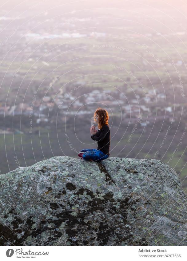 Junge Frau in Lotus-Pose meditiert auf einer Bergkuppe Yoga Sonnenuntergang Klippe Meditation padmasana Vitalität Zen üben Harmonie beweglich meditierend