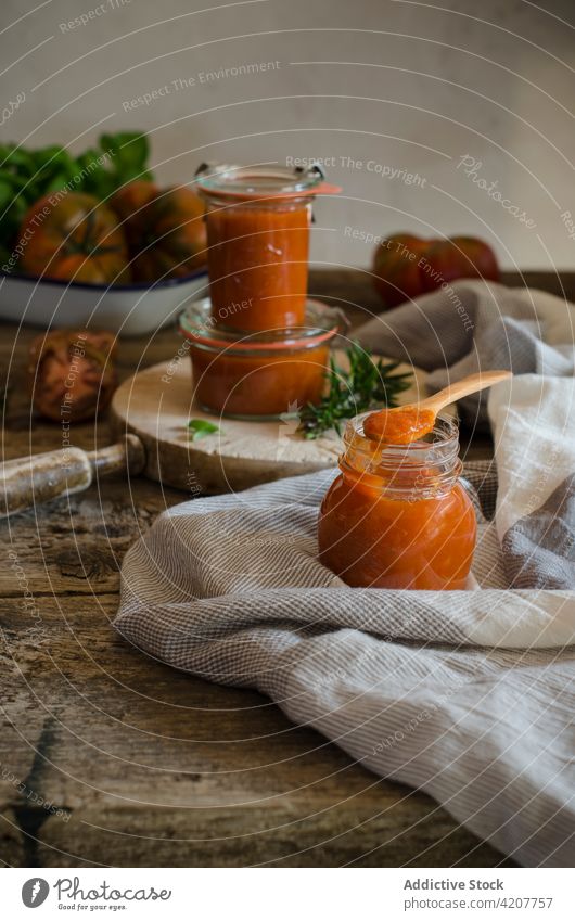 Glasgefäße mit hausgemachter gebratener Tomatensauce auf dem Tisch Saucen handgefertigt konservieren frisch Basilikum geschmackvoll Gewürz Küche organisch