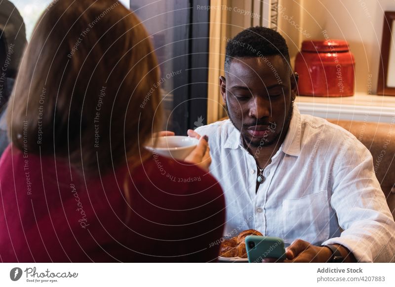 Gemischtrassiges Paar beim Frühstück in einem gemütlichen Café Zusammensein Partnerschaft Gespräch Fenster Morgen Liebe Lifestyle ruhen romantisch Kantine ernst