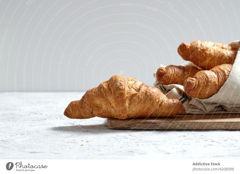 Süße Croissants auf Holzbrett auf Tisch Frühstück gebacken Mahlzeit Lebensmittel Bäckerei Morgen Dessert Leckerbissen hölzern Serviette Gebäck Tradition lecker