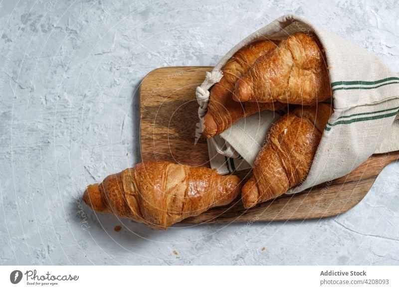 Süße Croissants auf Holzbrett auf Tisch Frühstück gebacken Mahlzeit Lebensmittel Bäckerei Morgen Dessert Leckerbissen hölzern Serviette Gebäck Tradition lecker