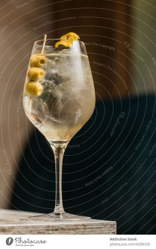 Ein Glas Cocktail mit Oliven Weinglas Martini Getränk Alkohol Tonic trinken Tisch Saum oliv Eis Schnaps hölzern Raum Kristalle Erfrischung Würfel durchsichtig