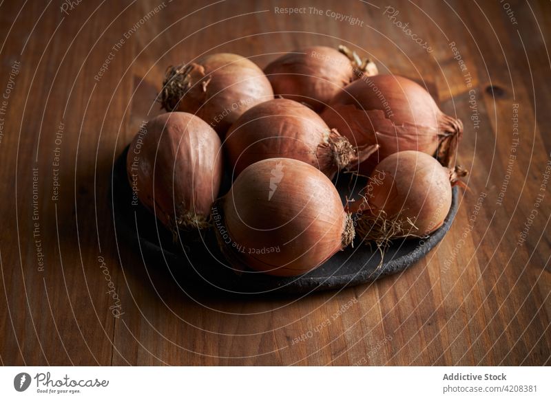 Ungeschälte rohe Zwiebeln auf dem Teller Tisch Haufen ungeschält organisch Lebensmittelgeschäft Bestandteil hölzern frisch Ernährung reif Nutzholz Küche Holz