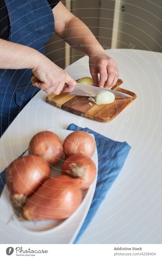 Hausfrau schneidet Zwiebel in der Küche Frau geschnitten Koch heimwärts organisch roh Schürze kulinarisch frisch Schneidebrett Messer Tisch Bestandteil Mahlzeit