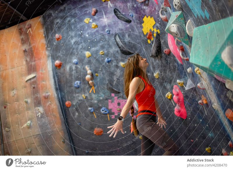 Aktive Frau klettert an der Wand im Fitnessstudio Sportlerin klettern Bouldern Fokus extrem Konzentration Stärke Training stark Bergsteiger aktiv sportlich