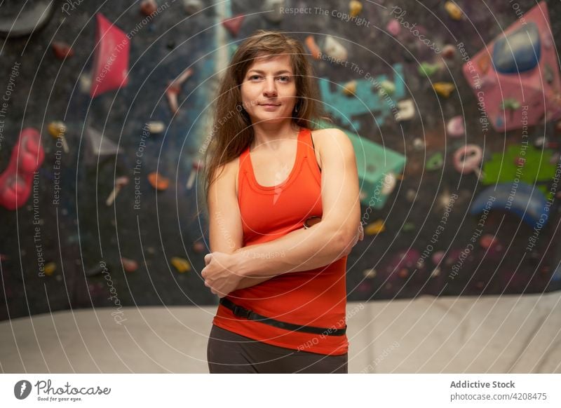 Sportlerin steht in der Nähe der Kletterwand in einer Turnhalle Bergsteiger Aufsteiger Wand Fitnessstudio Lächeln selbstbewusst passen Frau Gesundheit Athlet