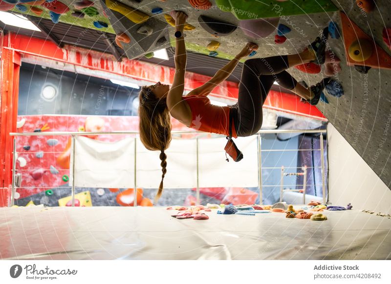 Aktive Frau klettert an der Wand im Fitnessstudio Sportlerin klettern Bouldern Fokus extrem Konzentration Stärke Training stark Bergsteiger aktiv sportlich