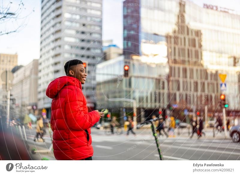 Porträt eines jungen Mannes, der auf einer Straße in der Stadt steht und lächelt schwarz außerhalb urban tausendjährig Stehen Afrikanisch im Freien Großstadt