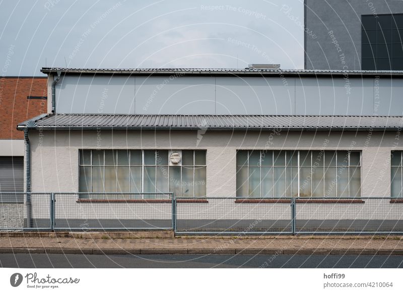 Lagerhalle mit Zaun und geschlossenen Fenstern trist wartezone 50ger Jahre Hafen Logistikbereich logistik Halle Schuppen Industrie Gebäude Fassade