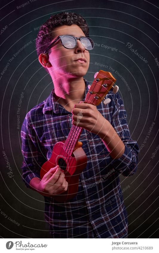 Portrail von jungen Teenager spielen die Ukulele mit schönen bunten Lichtern. Hintergrund Musik Baby Design Party Wasser Kind Person Mädchen altehrwürdig Mann