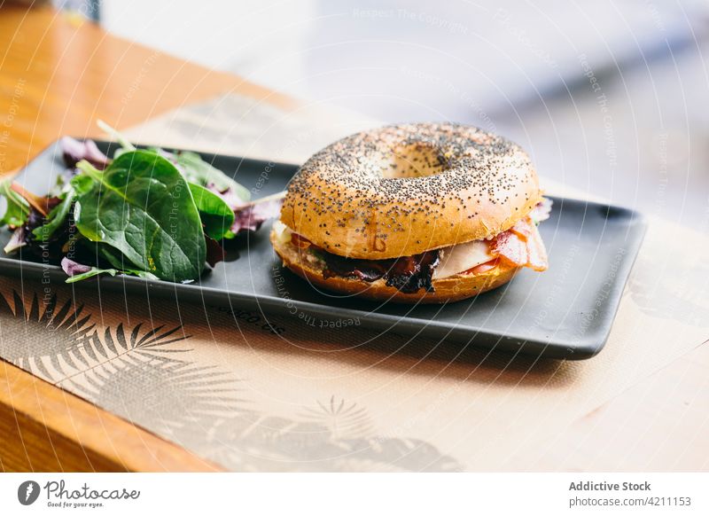 Leckeres Bagel-Sandwich auf dem Tisch im Café Belegtes Brot Fleisch dienen geschmackvoll Hähnchen appetitlich Lebensmittel Mahlzeit lecker Salatbeilage Teller