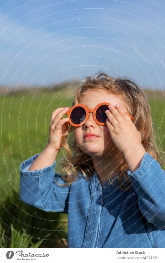 Stilvolles Mädchen auf Gras liegend ruhen Outfit Feld Rasen Wochenende Hand hinter dem Kopf Sommer Kind Saison Sonnenbrille trendy friedlich Kälte sorgenfrei