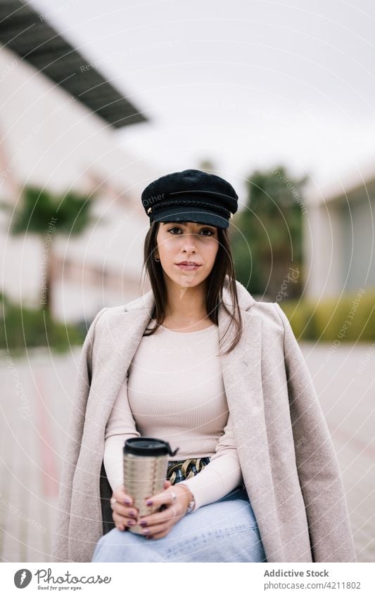 Geschäftsfrau auf einer Bank sitzend mit Kaffee zum Mitnehmen in einer Tasse Imbissbude Großstadt trendy Unternehmer Frau Outfit Getränk trinken Heißgetränk