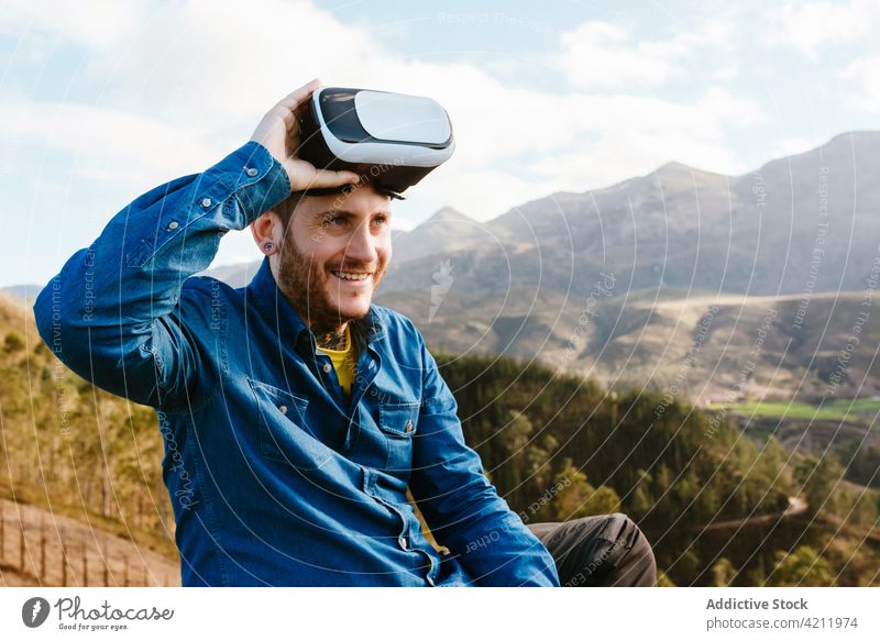 Reisender Mann mit VR-Brille in den Bergen virtuell Realität Berge u. Gebirge Erfahrung Hochland Schutzbrille reisen männlich Abenteuer genießen Hügel erkunden